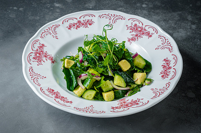 Healthy summer green salad with avocado, cucumbers, rucola, red onion, dressed with linseed oil